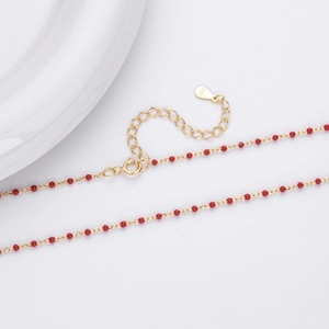 Detail shot of golden S925 sterling silver necklace with red beads and hallmark