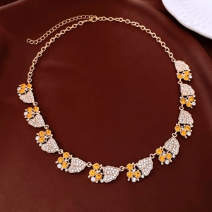 Close-up of golden leaf and berry pendant with orange rhinestones on silk