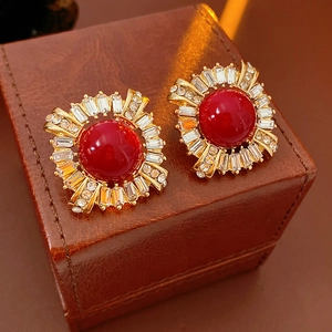 Macro detail of vintage gold stud earrings with red gemstones and zircon halo on leather
