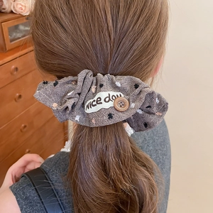 Close-up of brown plaid fabric scrunchie with a resin button and nice day patch