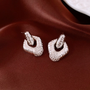 Macro detail of silver diamond-set geometric earrings on a vintage silk background