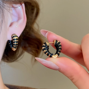 Détail de boucles d'oreilles cœur en or 18k avec texture tissée noire et finition polie