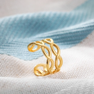 Detailed macro view of 18K gold-plated hollow woven ring on a soft linen background
