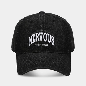 Close-up of white NERVOUS embroidery on black washed denim baseball cap with curved brim