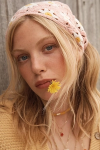 Close-up of a pink handmade crochet bandana with white daisy flowers on a model