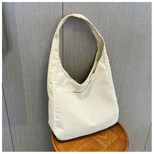 Detail der beigen Cord-Einkaufstasche mit weicher Rippenstruktur und vorderer Stecktasche