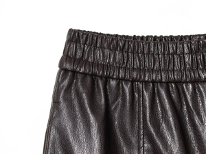 Close-up of high-waist elastic waistband and lychee texture on dark brown leather shorts