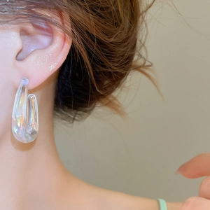 Close-up of iridescent acrylic C-shaped hoop earring on model with glossy finish