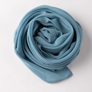 Detail of gray-blue chiffon scarf folded into a rose showing fine rolled hem and soft texture