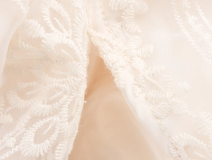 Detailed close-up of beige floral lace embroidery on layered mesh boho maxi dress