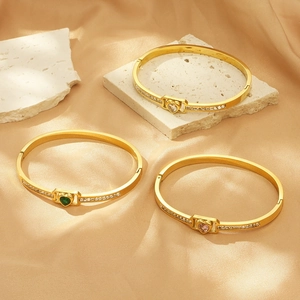 Golden open bangle with heart-shaped gemstones and sparkling side stones on satin
