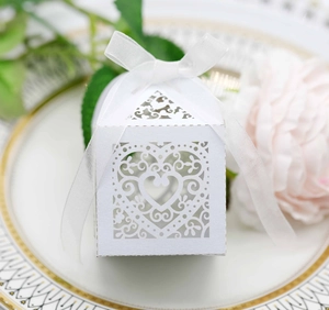 Detailed laser-cut heart pattern on a white pearl paper wedding favor box with ribbon