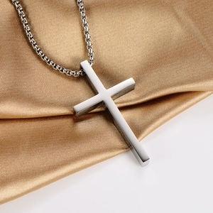 Polished silver stainless steel cross pendant necklace with box chain on gold silk fabric