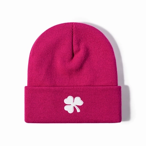 Magenta knitted beanie hat with white clover embroidery in a minimalist winter style