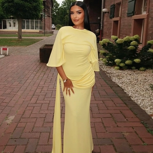 Close-up of elegant light yellow maxi dress with draped sleeves and waist pleats
