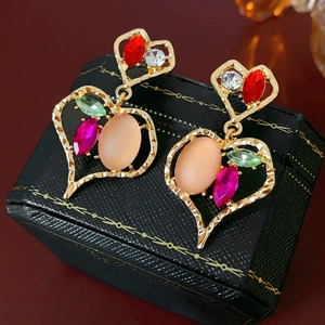 Vista macro di orecchini a cuore stile vintage con incastonate gemme multicolore