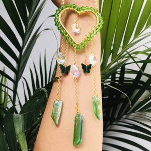 Golden heart suncatcher with green beads, crystals and butterfly pendant on palm leaf
