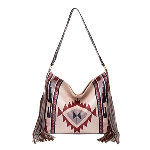 Close-up of bohemian woven tote bag showing geometric patterns and long side tassels
