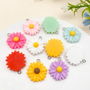Detailed view of colorful resin daisy pendants for jewelry making on a white plate