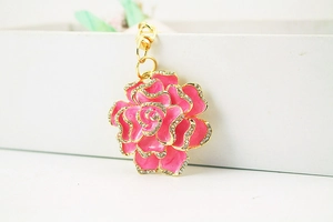Macro shot of pink enamel rose keychain with sparkling rhinestones on gold metal base