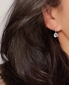 Close-up of a silver titanium steel earring with clear cubic zirconia on the earlobe
