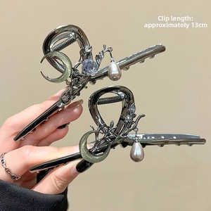 Close-up of a 13cm dark gray metal hair claw with moon, pearls and rhinestones
