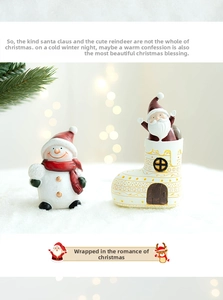 Close-up of ceramic Christmas snowman and Santa in boot house on snowy surface