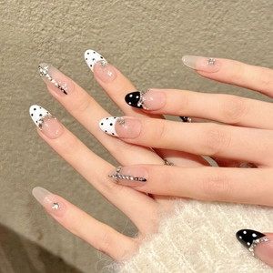 Unghie finte a pois con strass bianchi e neri su forma a mandorla elegante da donna