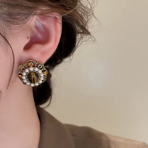 Close-up of vintage gold flower earrings with tiger eye stone and small white pearls