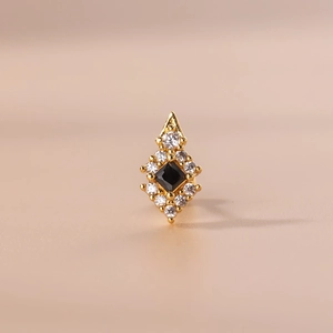Golden cartilage stud earring with square black zircon and clear crystals on a pink surface