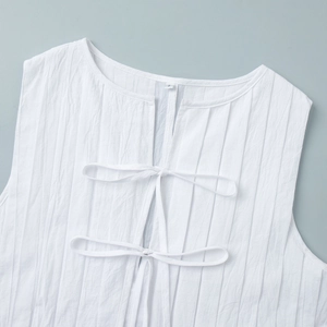 Gros plan détaillé sur l'encolure plissée et le design à lacets de cette robe blanche