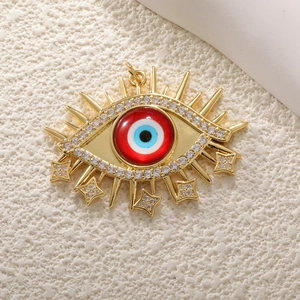 Detailed view of evil eye pendant with red eye motif and dangling zircon stars