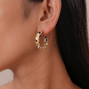 Gros plan d'une boucle d'oreille en chaîne dorée en forme de C avec motif léopard