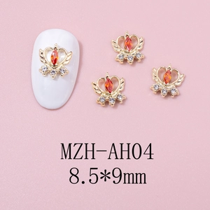 Macro detail of winged crown heart nail charm with red zircon and rhinestones