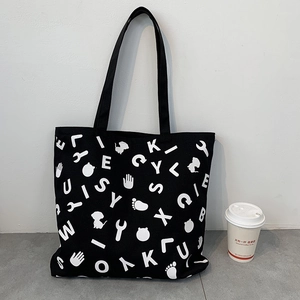 Detail of black canvas tote bag with white quirky prints and long shoulder handles