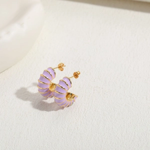 Macro shot of light purple enamel C-shaped earrings with spiral gold metallic thread details