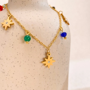 Macro shot of gold star charm bracelet with colorful beads and zircon on ceramic vase