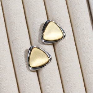 Close-up of geometric triangle stud earrings with brushed gold and silver metal finish