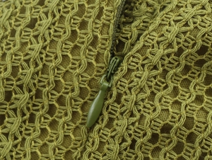Detail of olive green hollow knit fabric with hidden zipper on elegant halter dress