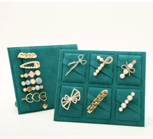 Detail of assorted pearl and metal hair clips displayed on a dark green velvet board