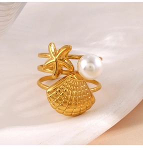 Macro detail of golden starfish, shell, and pearl elements on triple-layered open ring
