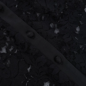 Macro detail of black floral lace fabric with matching buttons on long sleeve polo top