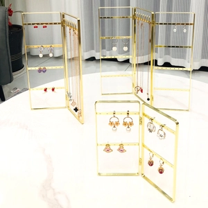 Detailed close-up of golden metal folding jewelry display rack with earrings and necklaces