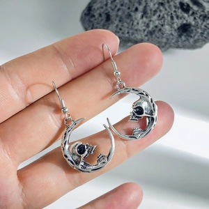 Macro detail of gothic skull moon earrings with vintage silver finish and metal texture