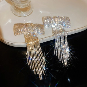 Détail de la pince à cheveux nœud à strass scintillants avec pompon doré et argent