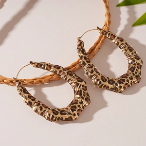 Detail of leopard print geometric earrings with bamboo texture on a white background
