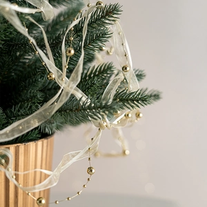 Nastro natalizio con perline dorate e organza su rami di pino verde per decoro