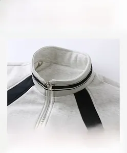 Detail of grey knit jacket showing stand collar with black stripes and silver metal zipper