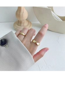 Close-up of minimalist gold twisted Mobius rings on fingers with modern aesthetic props