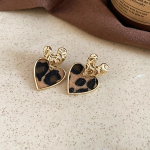 Detail of heart-shaped earrings with leopard print flocking and gold irregular metal